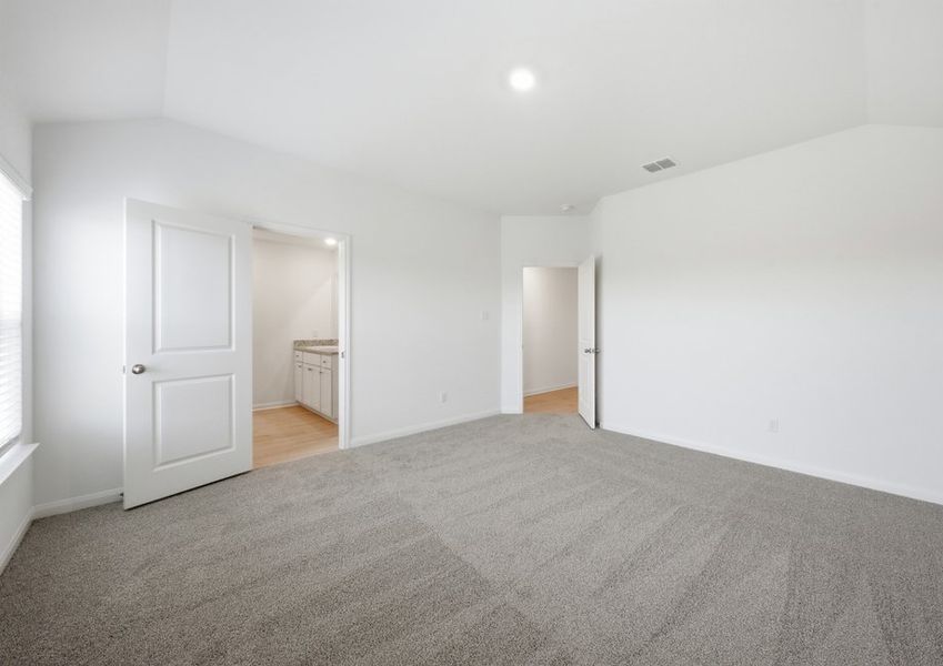 Primary bedroom featuring carpet flooring and a doorway to the ensuite master bath. Primary bedroom featuring carpet flooring and a doorway to the ensuite master bath.