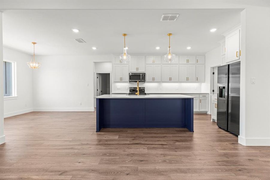 Kitchen with appliances with stainless steel finishes, recessed lighting, white cabinets, and wood finished floors