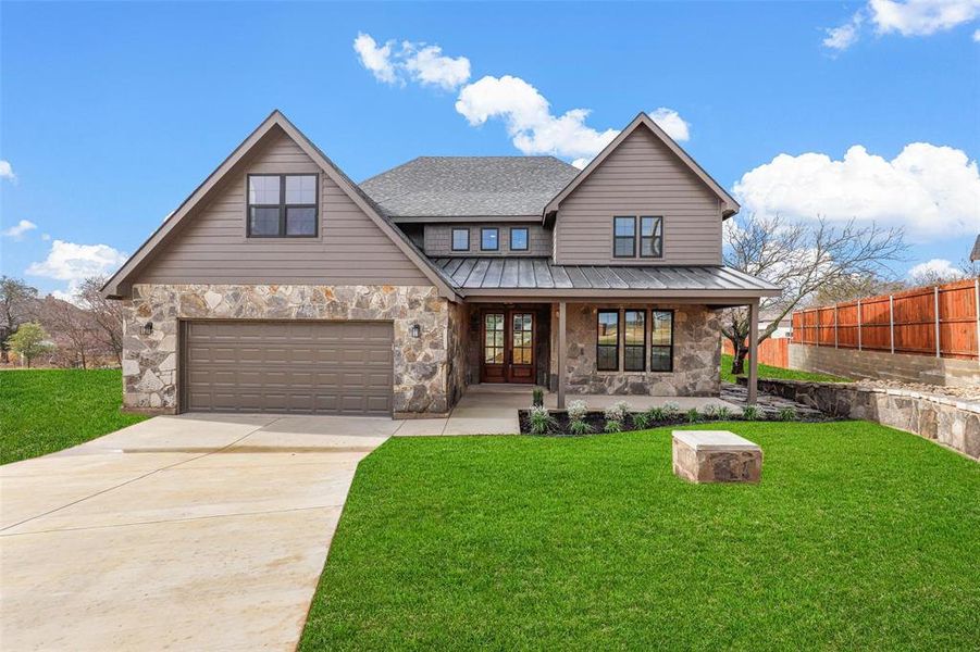 View of front of property with a porch, a garage, and a front lawn