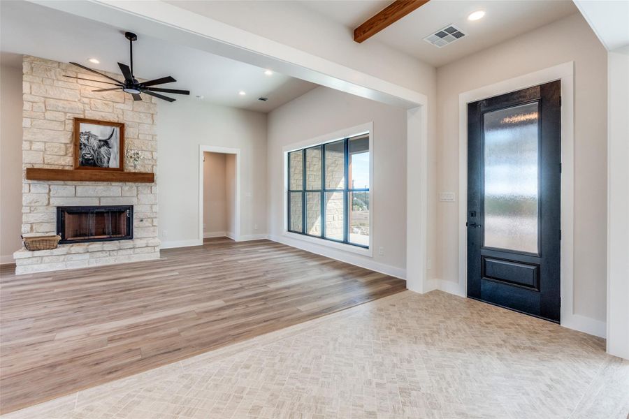 Entrance foyer featuring ceiling fan, a stone fireplace, recessed lighting, light wood-style floors, and beamed ceiling