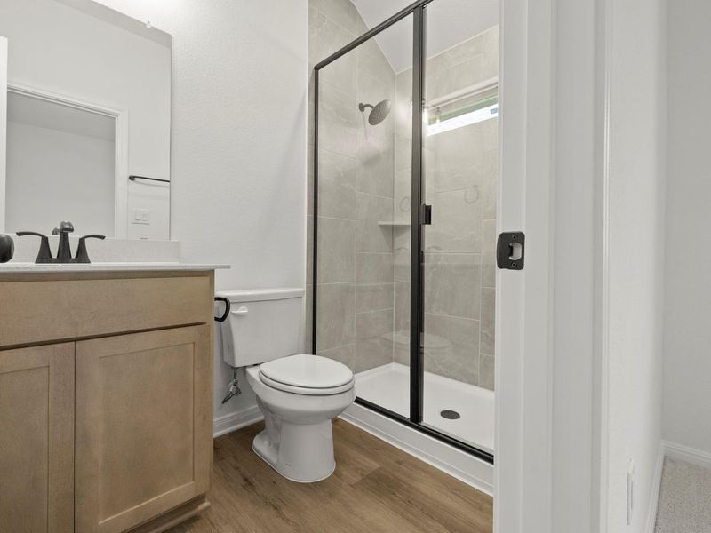 Contemporary bathroom featuring a walk-in shower with a black-framed glass enclosure, light-toned tile surround, and a built-in shower niche
