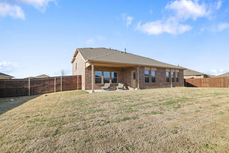 Rear view of house with a patio area, brick siding, a fenced backyard, and a shingled roof Rear view of house with a patio area, brick siding, a fenced backyard, and a shingled roof