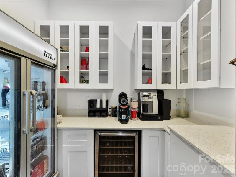 Convenient bar area with built-in cabinetry, beverage fridge, and countertop space perfect for entertaining and coffee service.