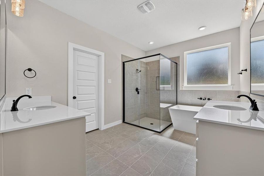 Bathroom featuring a glass-enclosed shower, freestanding tub, dual vanity with quartz countertops, and matte black fixtures Bathroom featuring a glass-enclosed shower, freestanding tub, dual vanity with quartz countertops, and matte black fixtures