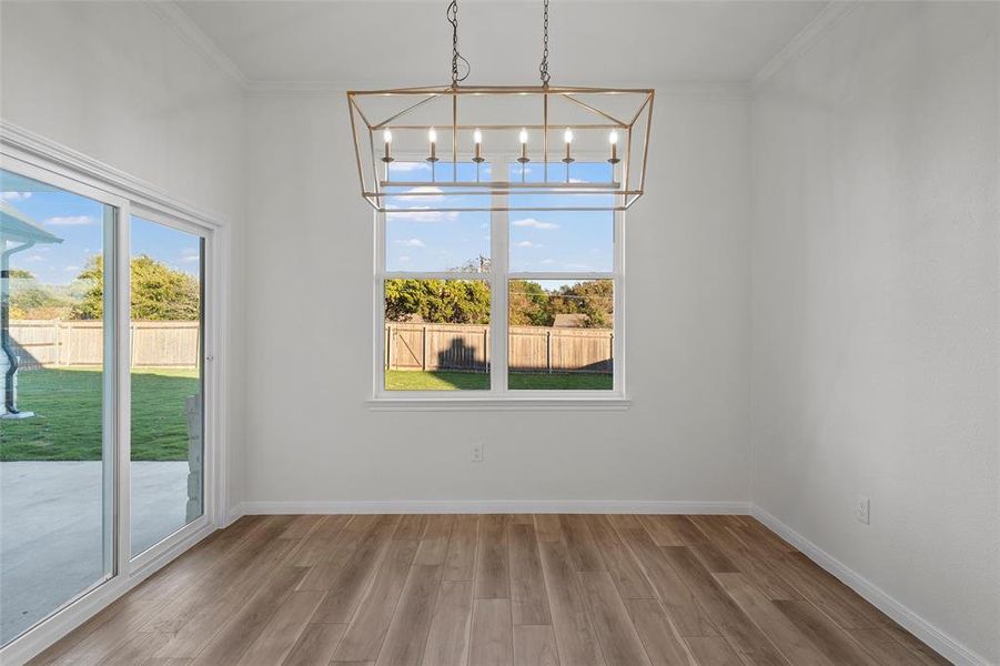 Unfurnished dining area featuring ornamental molding, light wood finished floors, and a chandelier
