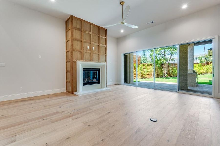 Unfurnished living room featuring light wood-style floors, a glass covered fireplace, recessed lighting, and a ceiling fan Unfurnished living room featuring light wood-style floors, a glass covered fireplace, recessed lighting, and a ceiling fan