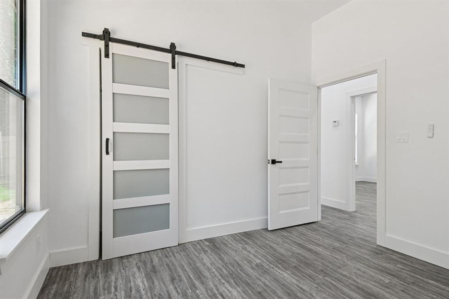 Unfurnished bedroom featuring a barn door and dark wood finished floors Unfurnished bedroom featuring a barn door and dark wood finished floors