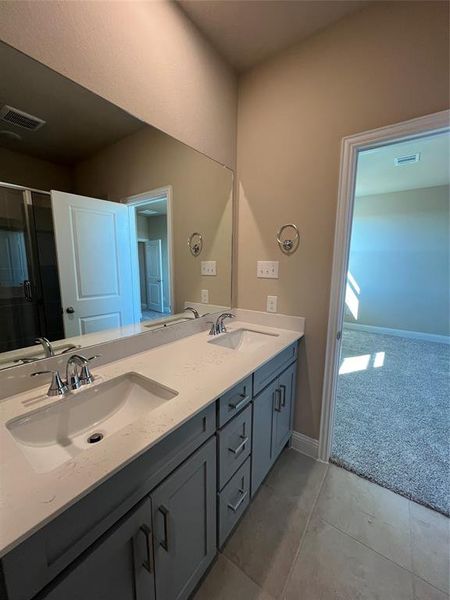 Full bath with double vanity, a sink, and visible vents