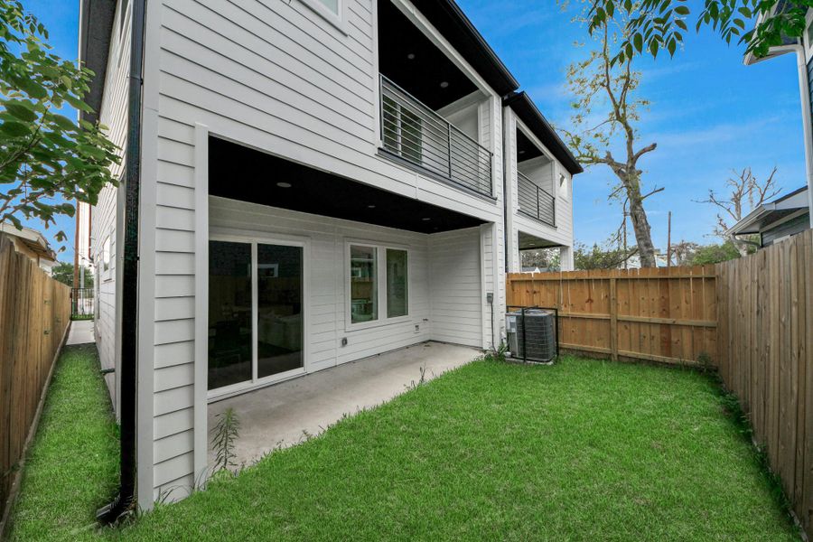 Discover serene outdoor living in this charming backyard, featuring a lush lawn, a cozy covered patio perfect for relaxation, and a modern, elegant façade that enhances the home's appeal.