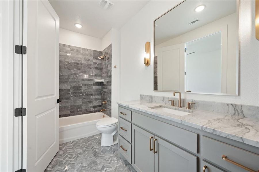 Full bathroom featuring tiled shower / bath combo, vanity, and toilet