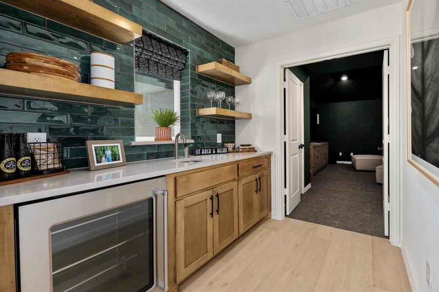 Wet Bar with light hardwood / wood-style floors, wine cooler, sink, and backsplash