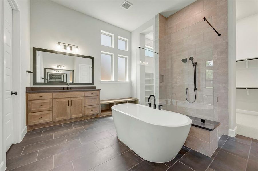 Bathroom with a stall shower, vanity, a soaking tub, dark tile patterned flooring, and a walk in closet