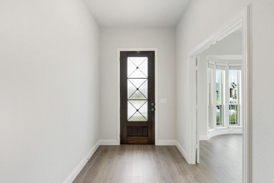 Entryway with dark wood front door featuring glass panels and light hardwood floors Entryway with dark wood front door featuring glass panels and light hardwood floors