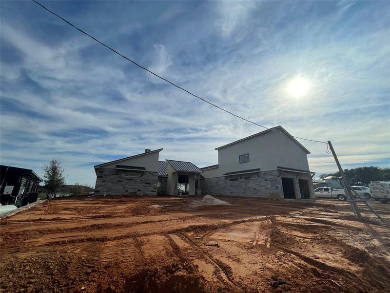 Back of house with stone siding and stucco siding