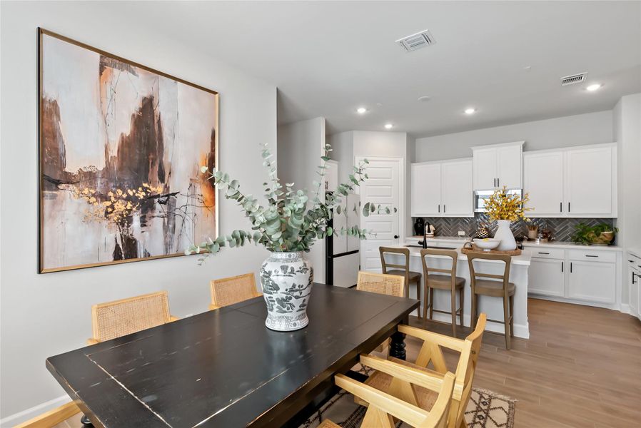 Dining room with light wood finished floors and recessed lighting