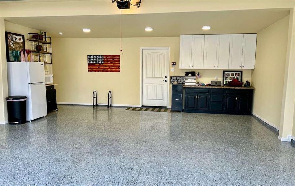 Garage featuring a garage door opener and white fridge