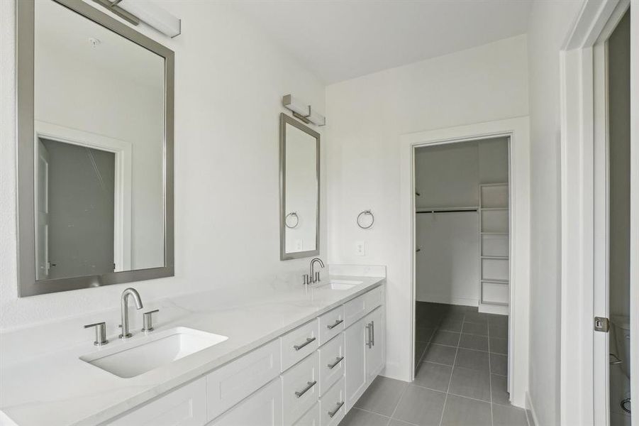 Full bathroom featuring tile patterned flooring, double vanity, and a spacious closet