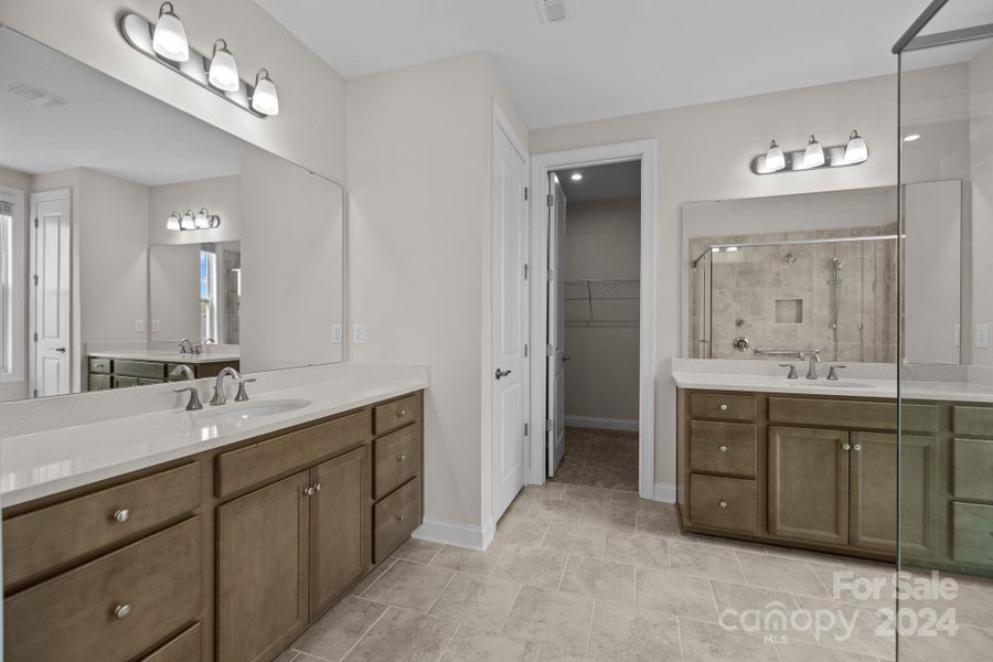 Primary ensuite Bath with tile floors and separate dual vanities with quartz counters.