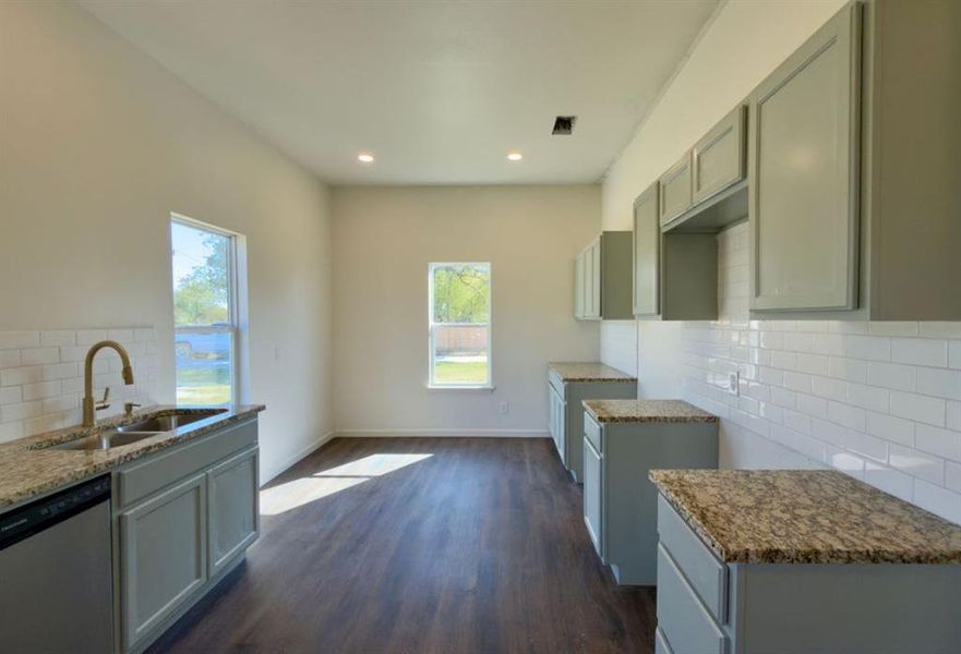 Kitchen with tasteful backsplash, stainless steel dishwasher, dark wood-style flooring, healthy amount of natural light, and recessed lighting Kitchen with tasteful backsplash, stainless steel dishwasher, dark wood-style flooring, healthy amount of natural light, and recessed lighting