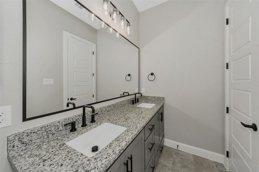 Bathroom with double vanity and baseboards