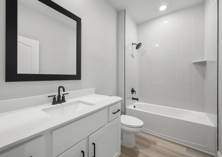 Second bathroom with a framed mirror and tile detail around the tub