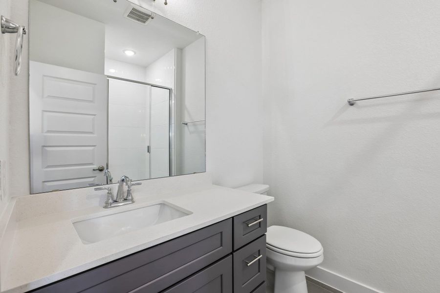 The guest bathroom featuresa quartz vanity.