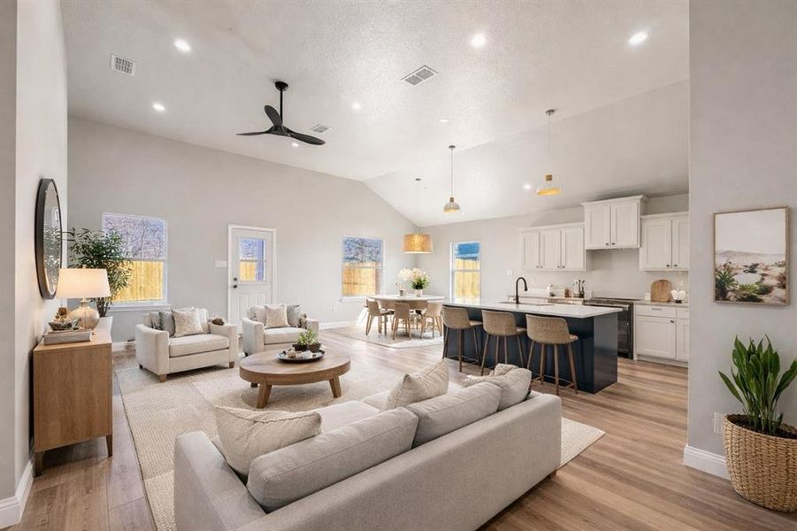 Living area featuring light wood-style flooring, lofted ceiling, a ceiling fan, and recessed lighting Living area featuring light wood-style flooring, lofted ceiling, a ceiling fan, and recessed lighting
