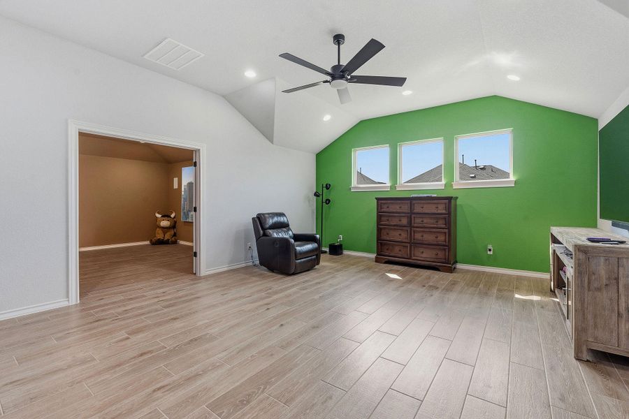 A vibrant green accent wall adds a playful touch to this sun-filled living space, complete with a modern ceiling fan and recessed lighting. A vibrant green accent wall adds a playful touch to this sun-filled living space, complete with a modern ceiling fan and recessed lighting.