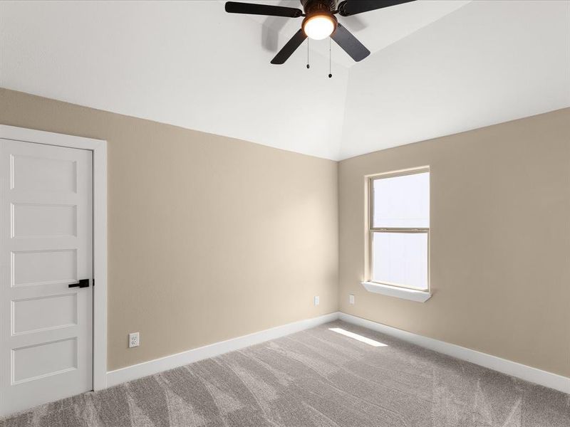 Carpeted spare room with a ceiling fan and lofted ceiling