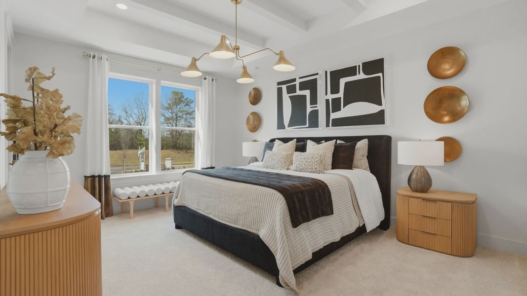 Spacious bright primary suite with carpet flooring, overhead lighting, and large window in the Seaton at Barrett Pointe.