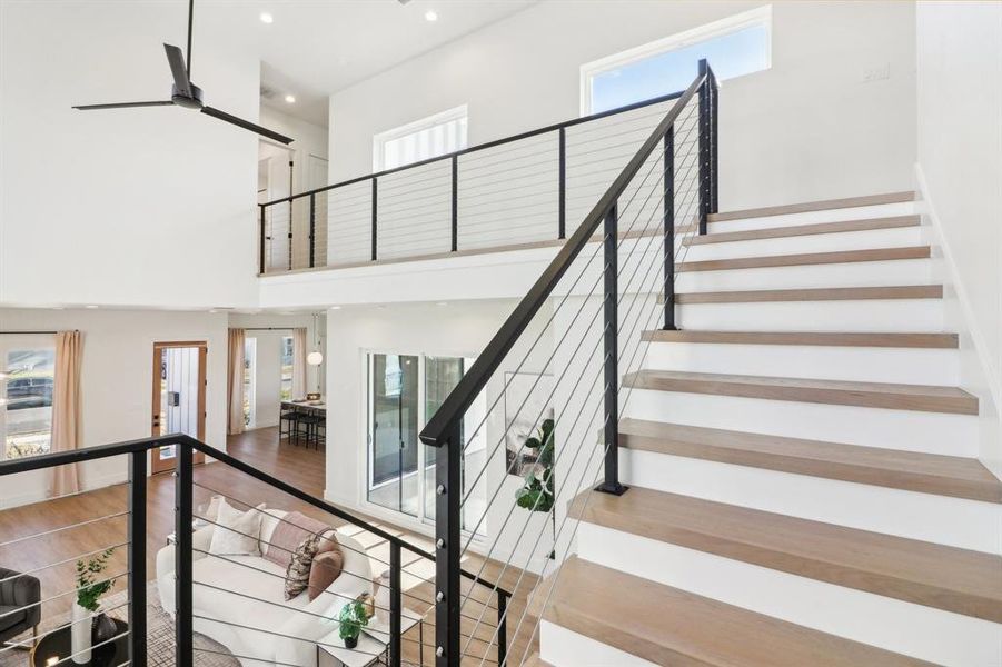 Stairway featuring a healthy amount of sunlight, hardwood / wood-style flooring, and a high ceiling