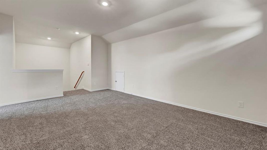 Spacious room featuring gray speckled carpeting, white painted walls, and recessed lighting