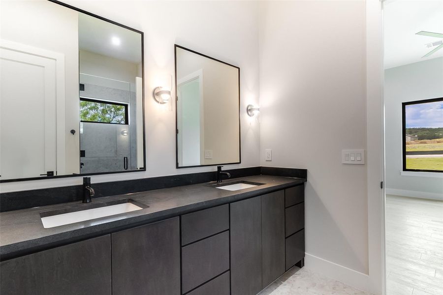 Bathroom with double vanity, baseboards, and a shower with shower door Bathroom with double vanity, baseboards, and a shower with shower door