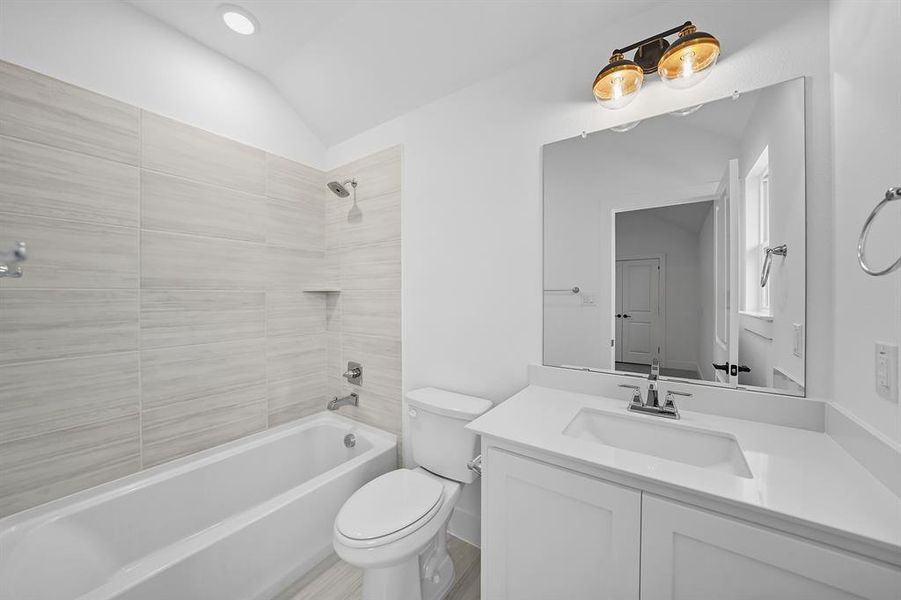 Full bath featuring  shower combination, vaulted ceiling, and vanity