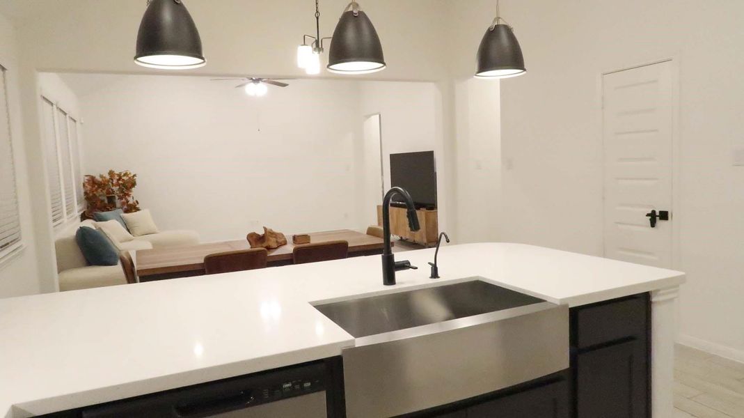 This photo showcases a modern, open-concept kitchen and living area. The kitchen features a sleek island with a stainless-steel sink and stylish pendant lighting. The living area includes ample natural light from multiple windows. This photo showcases a modern, open-concept kitchen and living area. The kitchen features a sleek island with a stainless-steel sink and stylish pendant lighting. The living area includes ample natural light from multiple windows.