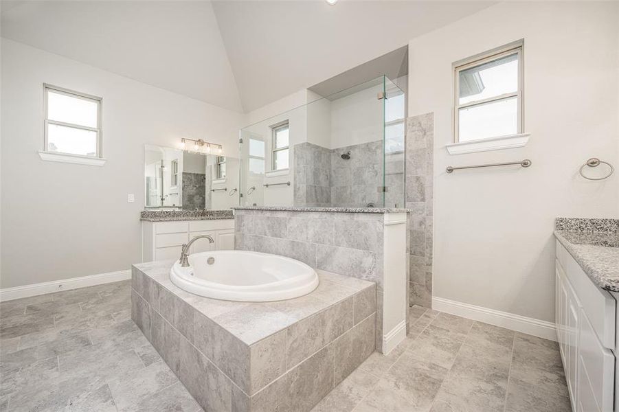 Bathroom with vanity, lofted ceiling, tile patterned flooring, and a healthy amount of sunlight