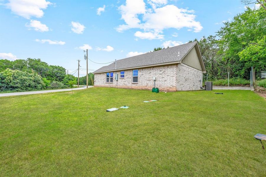 Rear view of property with central AC unit, a yard, brick siding, and a shingled roof Rear view of property with central AC unit, a yard, brick siding, and a shingled roof