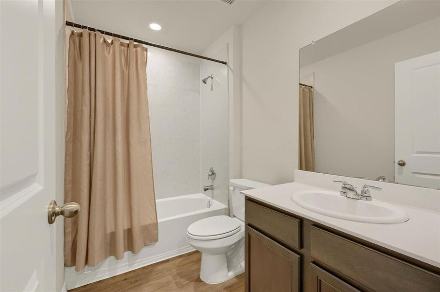 Full bathroom featuring hardwood / wood-style floors, toilet, vanity, and shower / bath combination with curtain