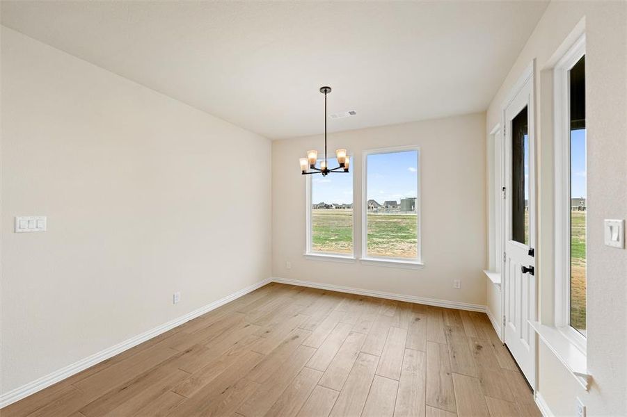 Unfurnished dining area featuring light wood finished floors and a chandelier