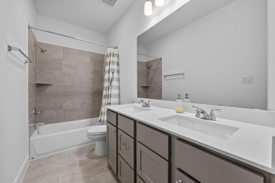 Full bathroom with shower / tub combo with curtain, double vanity, and light tile patterned flooring