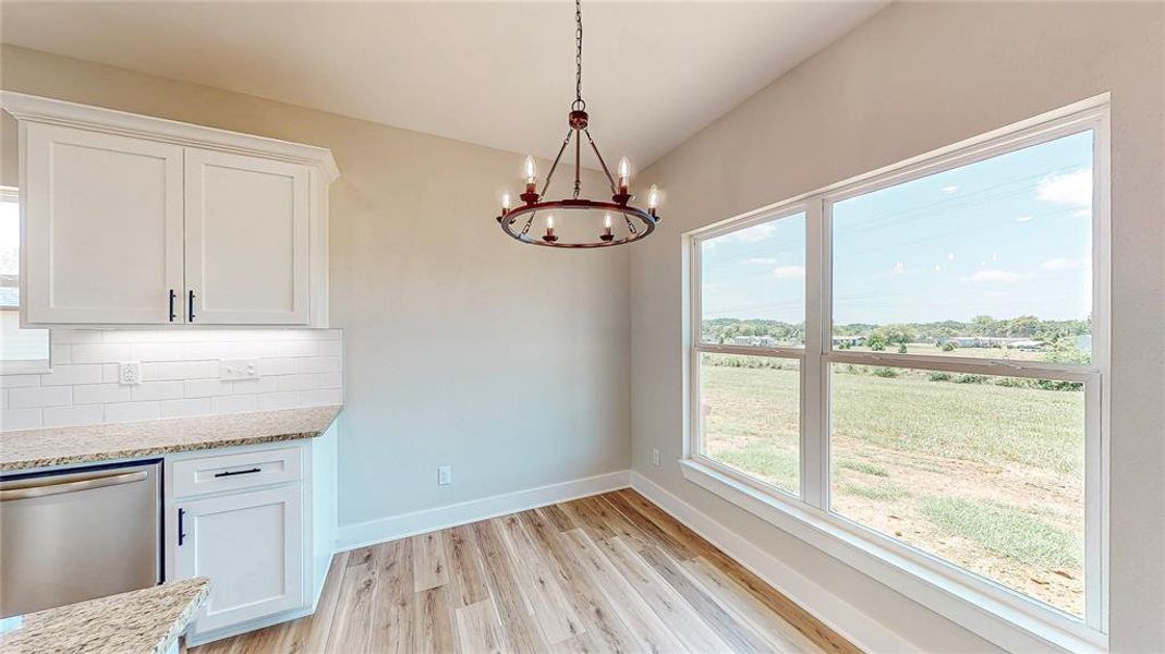 Unfurnished dining area featuring a chandelier, light wood finished floors, and vaulted ceiling Unfurnished dining area featuring a chandelier, light wood finished floors, and vaulted ceiling