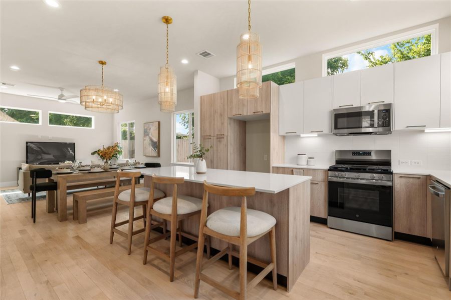 Open-concept layout seamlessly connecting the kitchen, dining & living areas, perfect for everyday living or entertaining guests, all enhanced by warm natural light.