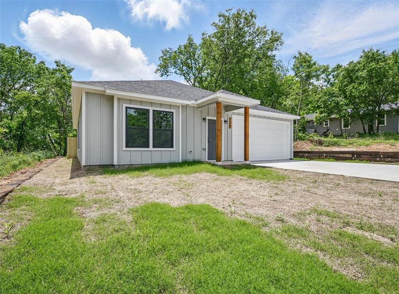 View of front of home with board and batten siding, concrete driveway, a front yard, a shingled roof, and a garage