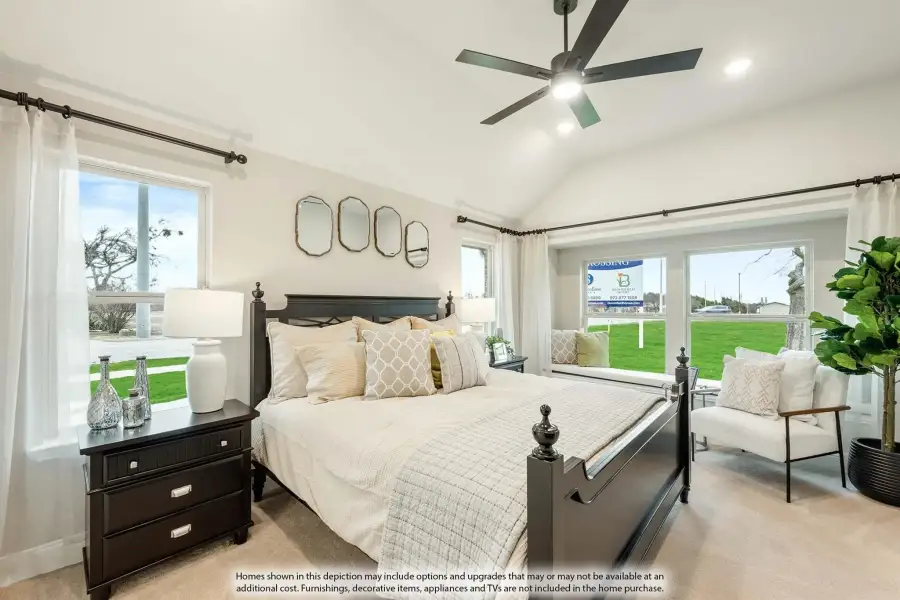 Bedroom with vaulted ceiling, dark wood four-poster bed, ceiling fan, and large windows with backyard views.
