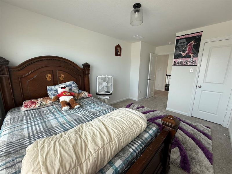 Carpeted bedroom with a clear glass flush mount ceiling light fixture, white interior doors, and neutral wall paint