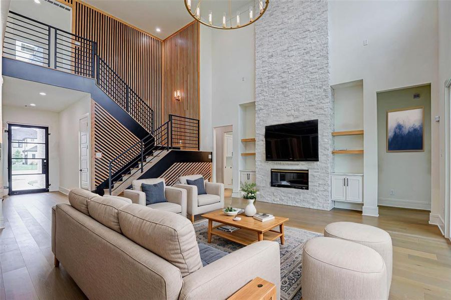 Living area with a high ceiling, light wood-style floors, a fireplace, a chandelier, and recessed lighting