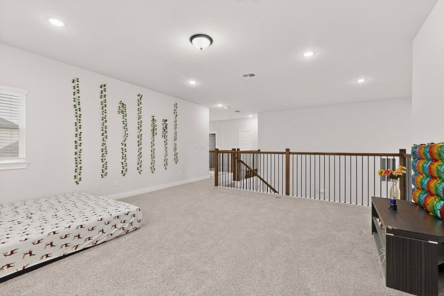 Living area with carpet floors, an upstairs landing, and recessed lighting