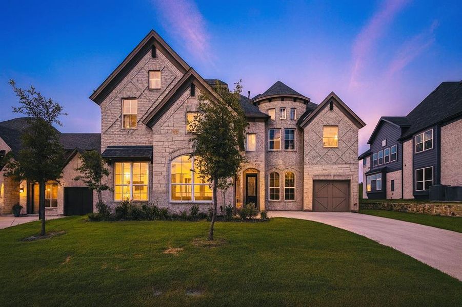 French provincial home with driveway, stone siding, a front lawn, an attached garage, and brick siding