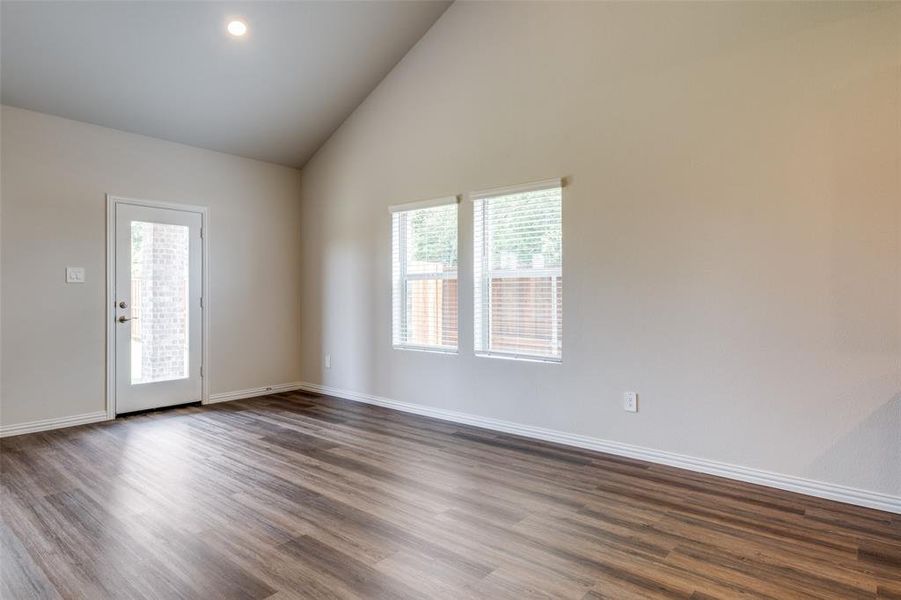 Empty room with high vaulted ceiling and dark wood-type flooring