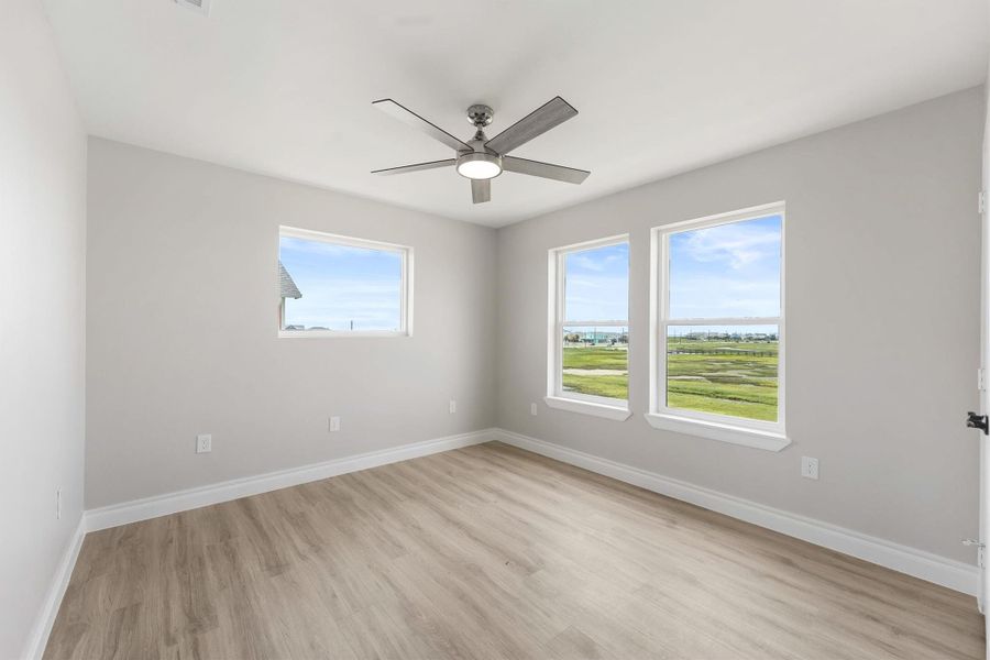 Bright and airy room with large windows offering scenic views, light wood flooring, neutral walls, and a modern ceiling fan. Bright and airy room with large windows offering scenic views, light wood flooring, neutral walls, and a modern ceiling fan.
